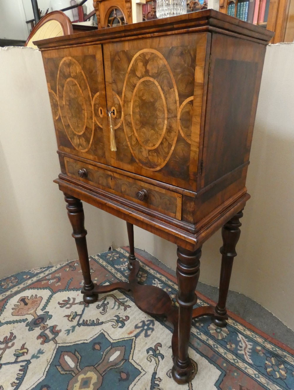 A late 17th-century olive wood cabinet on stand featuring oval oyster veneer patterns, a single drawer, and turned legs with a shaped stretcher. View II