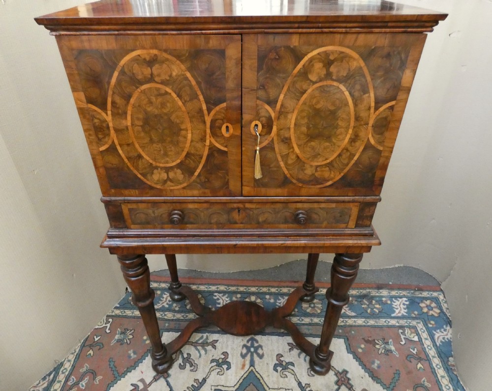 A late 17th-century olive wood cabinet on stand featuring oval oyster veneer patterns, a single drawer, and turned legs with a shaped stretcher. View V