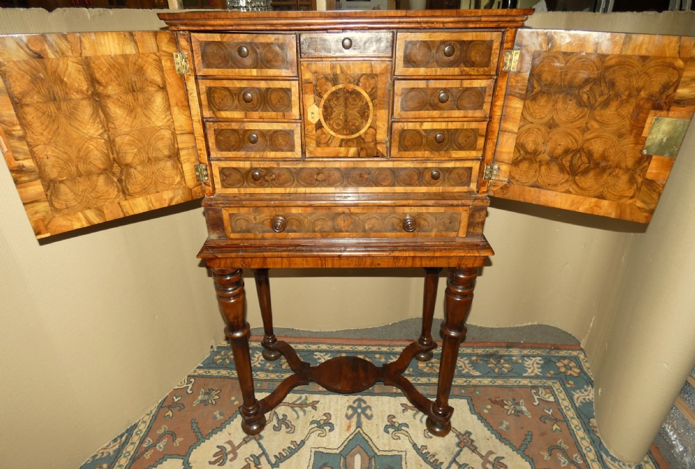 A late 17th-century olive wood cabinet on stand featuring oval oyster veneer patterns, a single drawer, and turned legs with a shaped stretcher. View VI