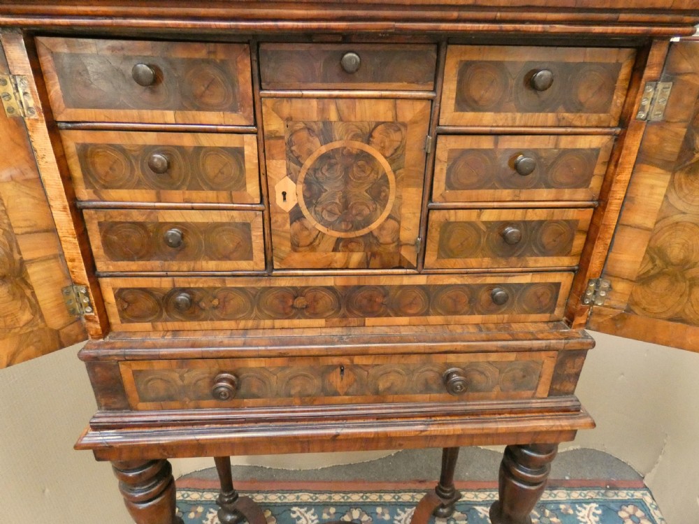 A late 17th-century olive wood cabinet on stand featuring oval oyster veneer patterns, a single drawer, and turned legs with a shaped stretcher. View VII