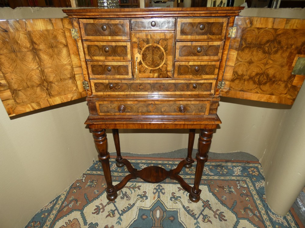 A late 17th-century olive wood cabinet on stand featuring oval oyster veneer patterns, a single drawer, and turned legs with a shaped stretcher. View X