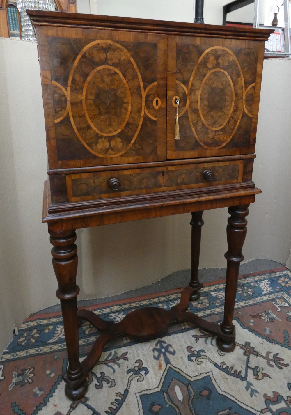 A late 17th-century olive wood cabinet on stand featuring oval oyster veneer patterns, a single drawer, and turned legs with a shaped stretcher. View XI