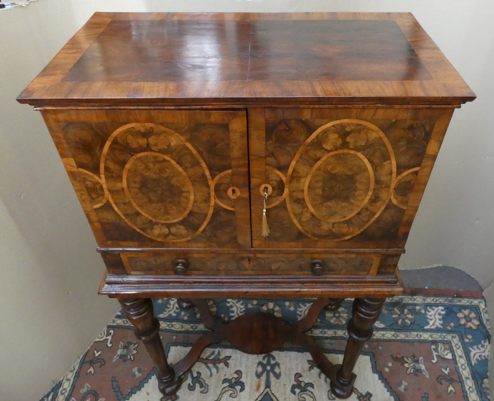 A late 17th-century olive wood cabinet on stand featuring oval oyster veneer patterns, a single drawer, and turned legs with a shaped stretcher. View XII