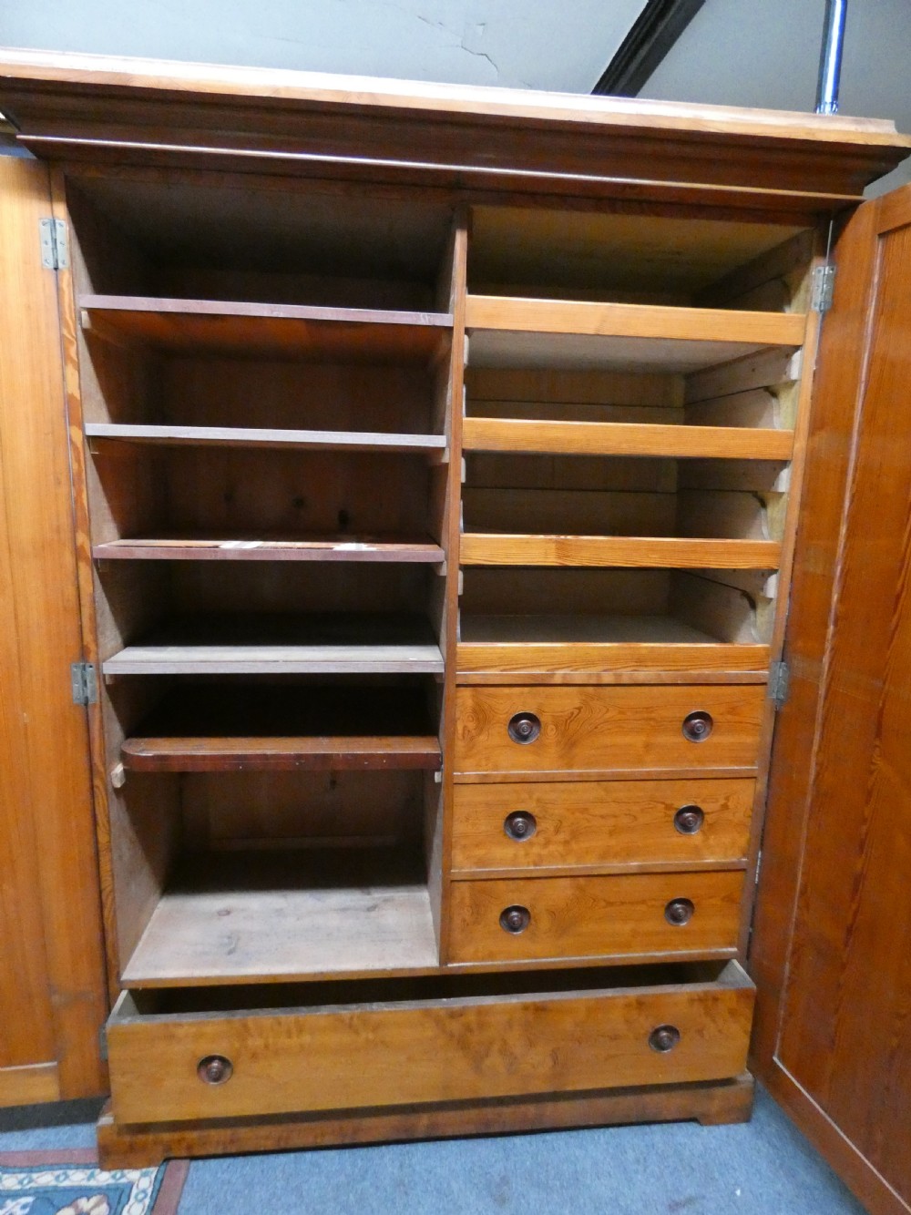A tall Victorian pine housekeepers cupboard featuring two vertical plank-panelled doors, a projected moulded top cornice, and a sturdy plinth base. View V