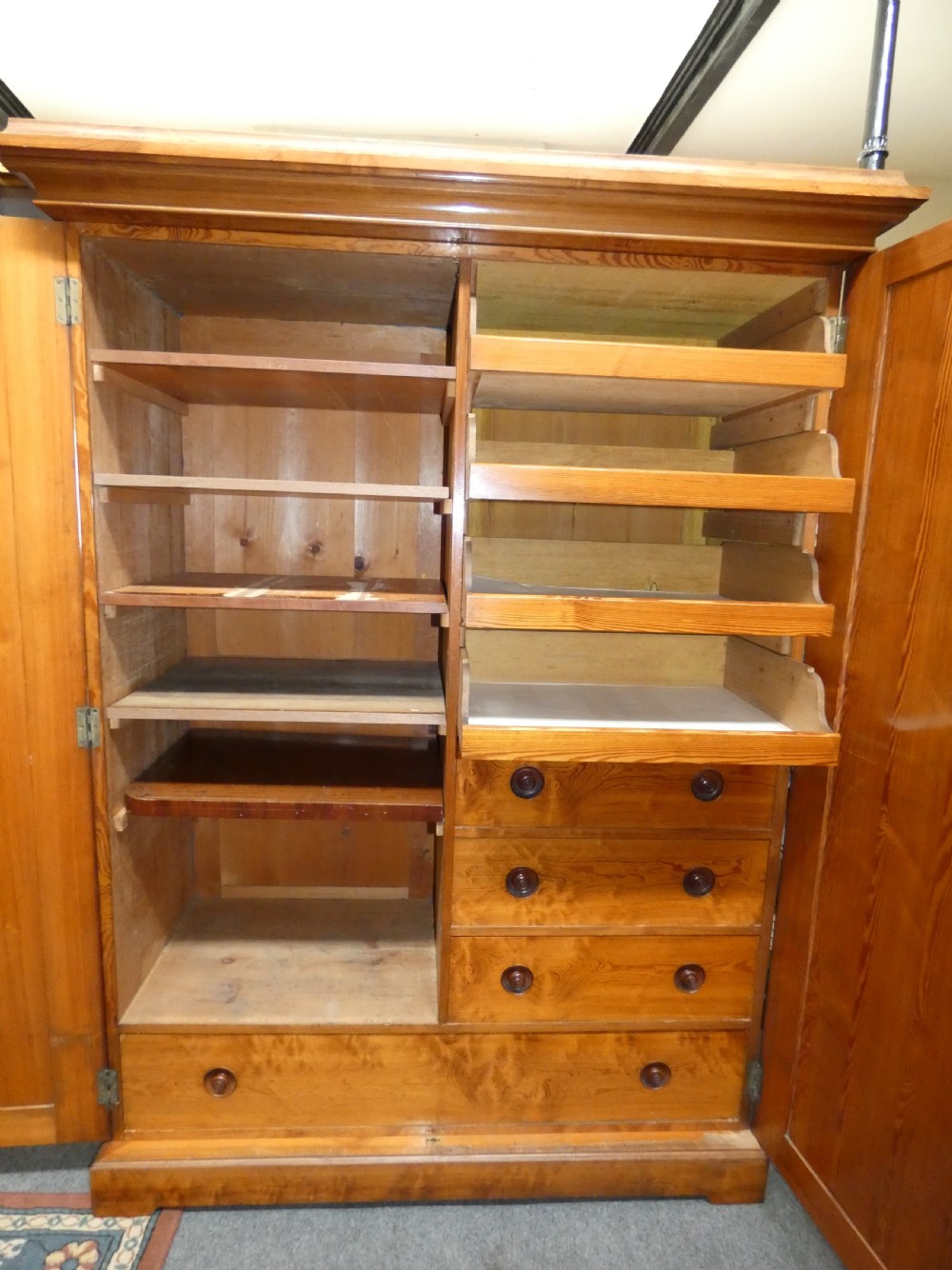 A tall Victorian pine housekeepers cupboard featuring two vertical plank-panelled doors, a projected moulded top cornice, and a sturdy plinth base. View VI
