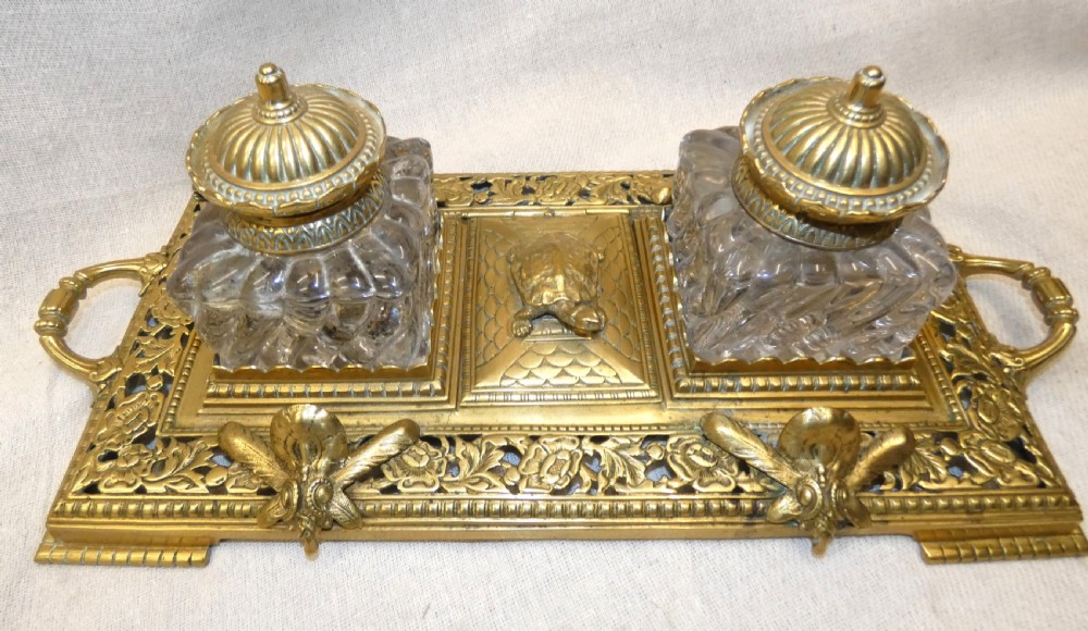 An ornate Victorian cast brass inkstand featuring twin faceted glass inkwells, a central tortoise motif, insect pen rests, and pierced scrollwork. View II