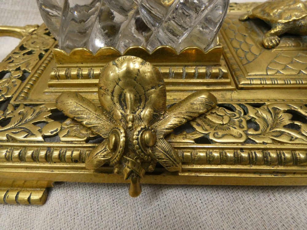An ornate Victorian cast brass inkstand featuring twin faceted glass inkwells, a central tortoise motif, insect pen rests, and pierced scrollwork. View III