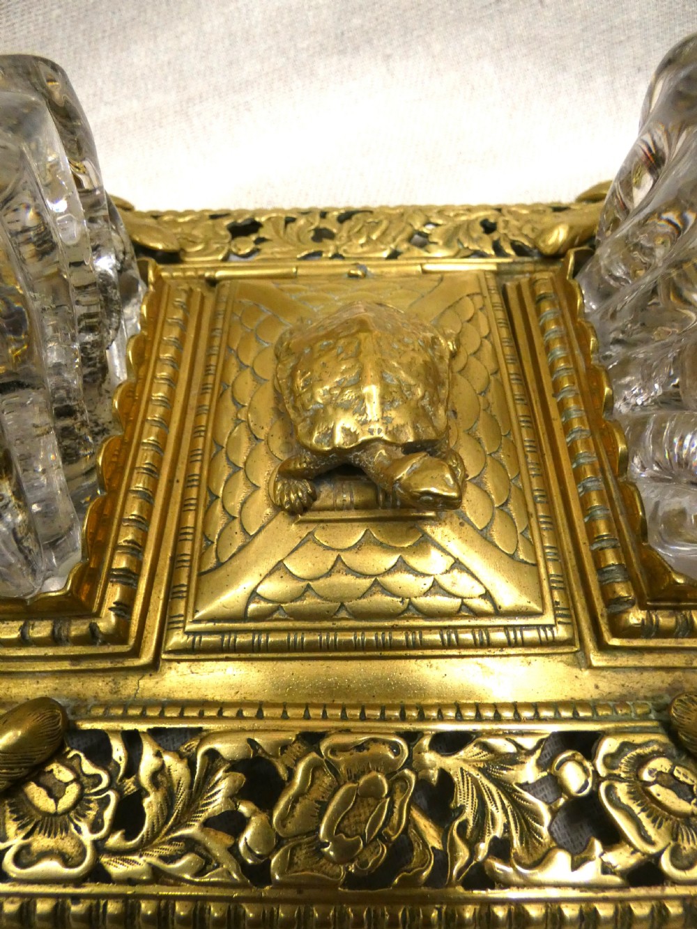 An ornate Victorian cast brass inkstand featuring twin faceted glass inkwells, a central tortoise motif, insect pen rests, and pierced scrollwork. View V