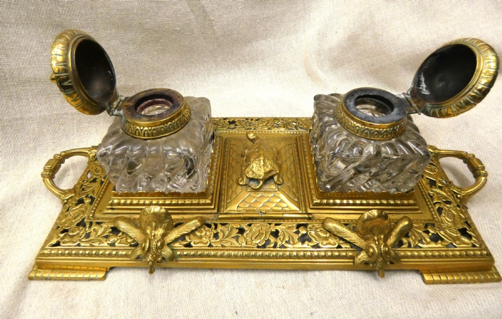 An ornate Victorian cast brass inkstand featuring twin faceted glass inkwells, a central tortoise motif, insect pen rests, and pierced scrollwork. View VIII