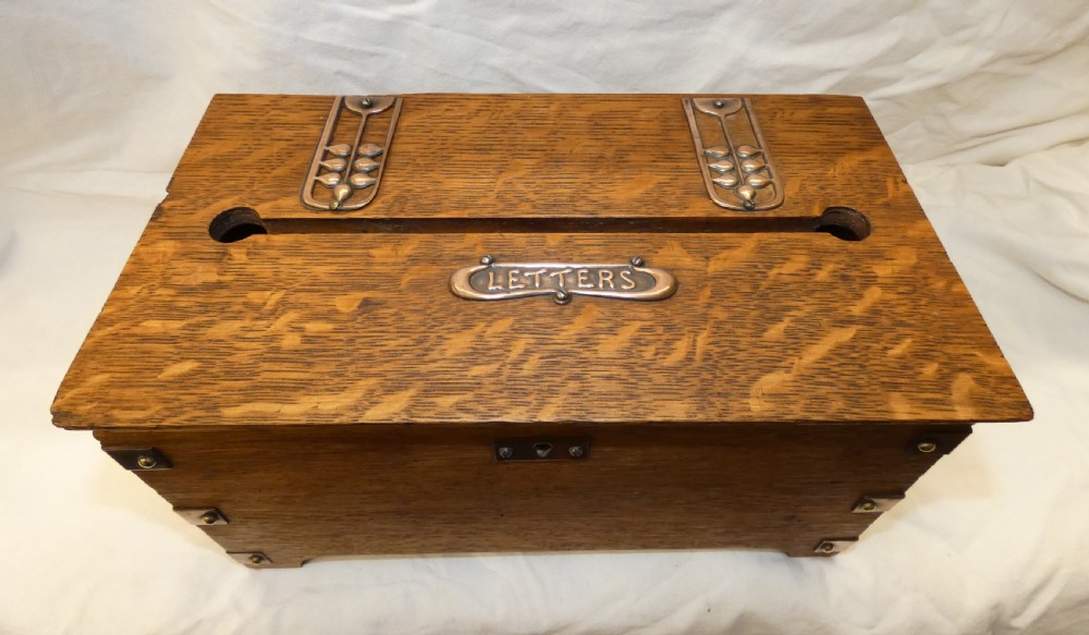 An antique Arts and Crafts solid oak letter box featuring decorative copper strap hinges, corner brackets, a top letter slot, and a central embossed copper plaque reading LETTERS. View II