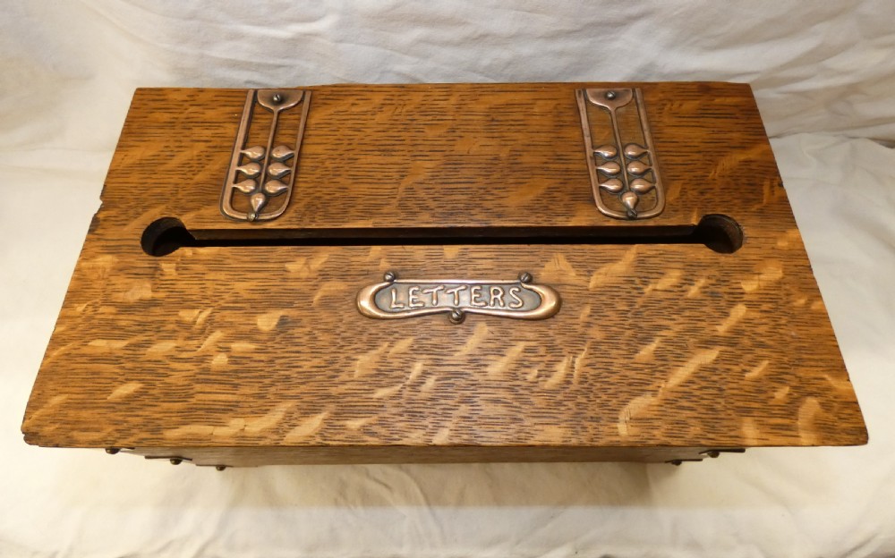 An antique Arts and Crafts solid oak letter box featuring decorative copper strap hinges, corner brackets, a top letter slot, and a central embossed copper plaque reading LETTERS. View III