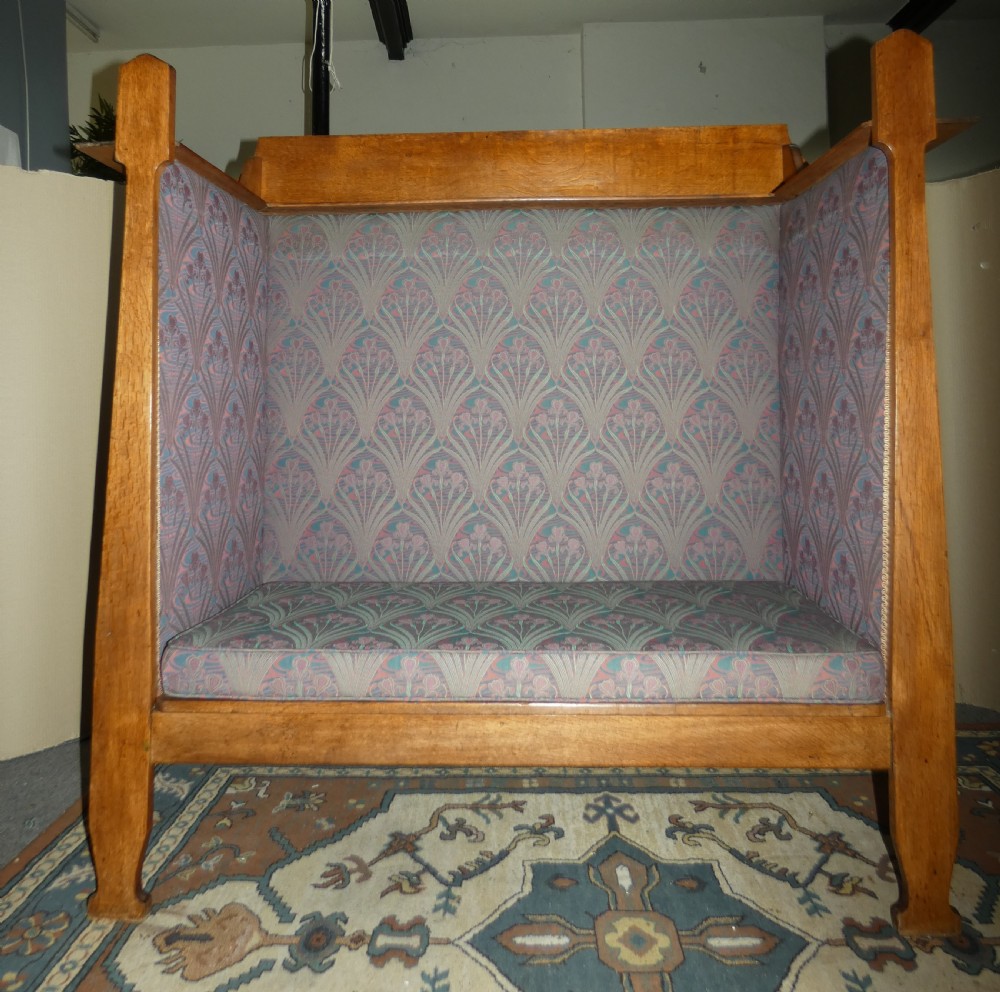An Arts and Crafts period solid oak high-back settle featuring upholstered side panels and a cushioned seat. View II