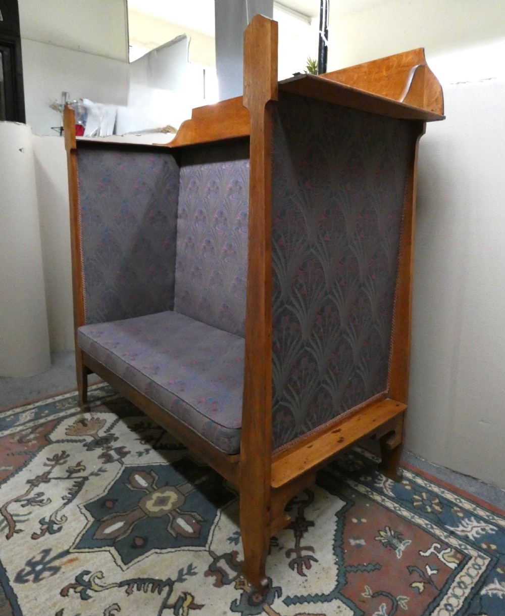 An Arts and Crafts period solid oak high-back settle featuring upholstered side panels and a cushioned seat. View III