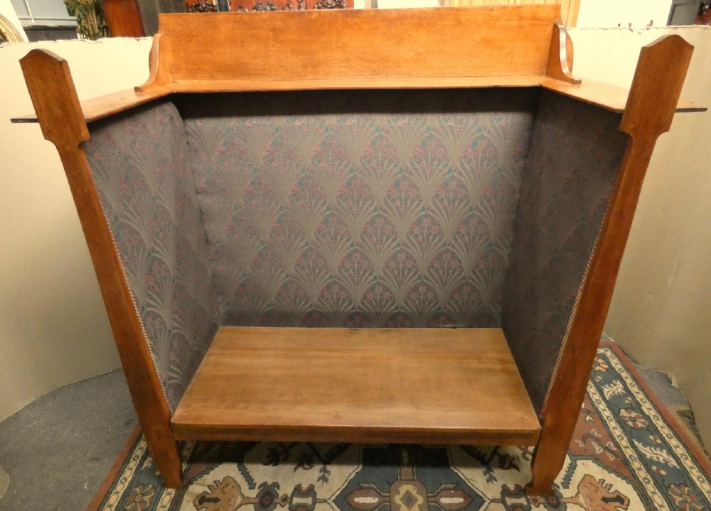 An Arts and Crafts period solid oak high-back settle featuring upholstered side panels and a cushioned seat. View VII