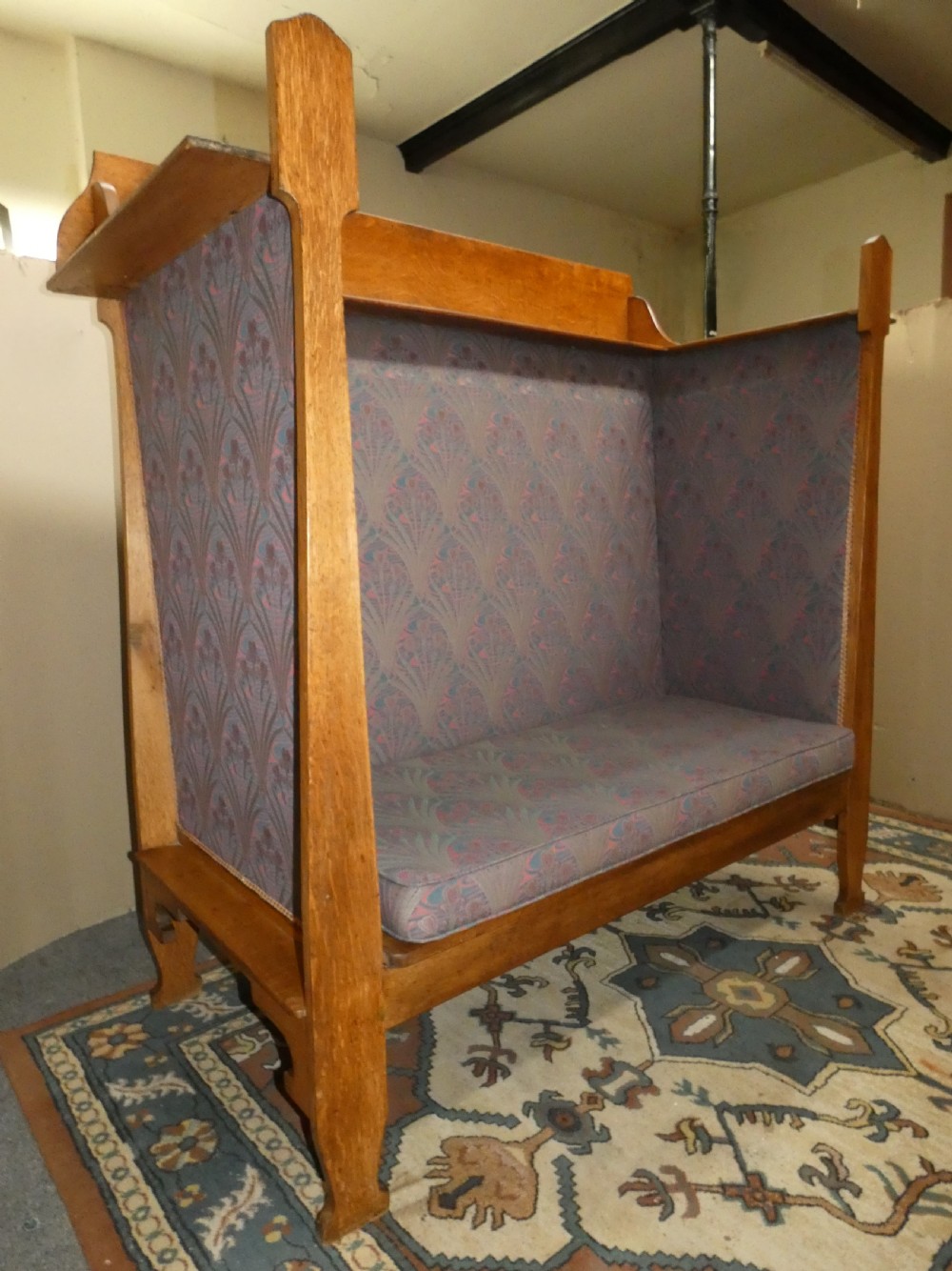 An Arts and Crafts period solid oak high-back settle featuring upholstered side panels and a cushioned seat. View VIII