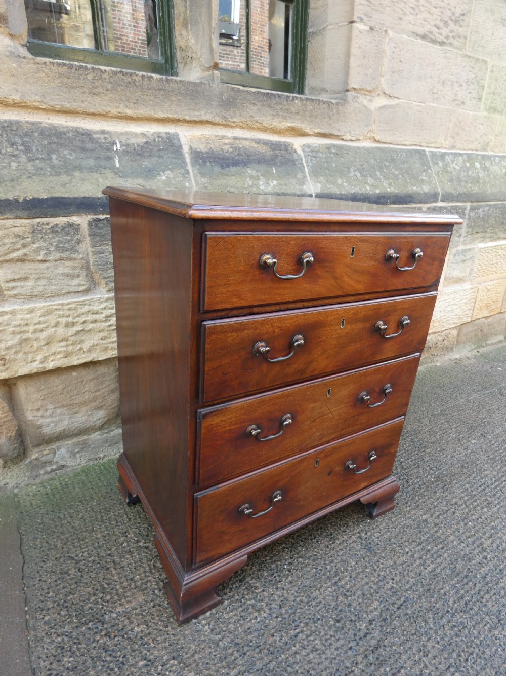 A small Georgian mahogany chest featuring four graduated drawers with brass swan-neck handles and bracket feet. View VII