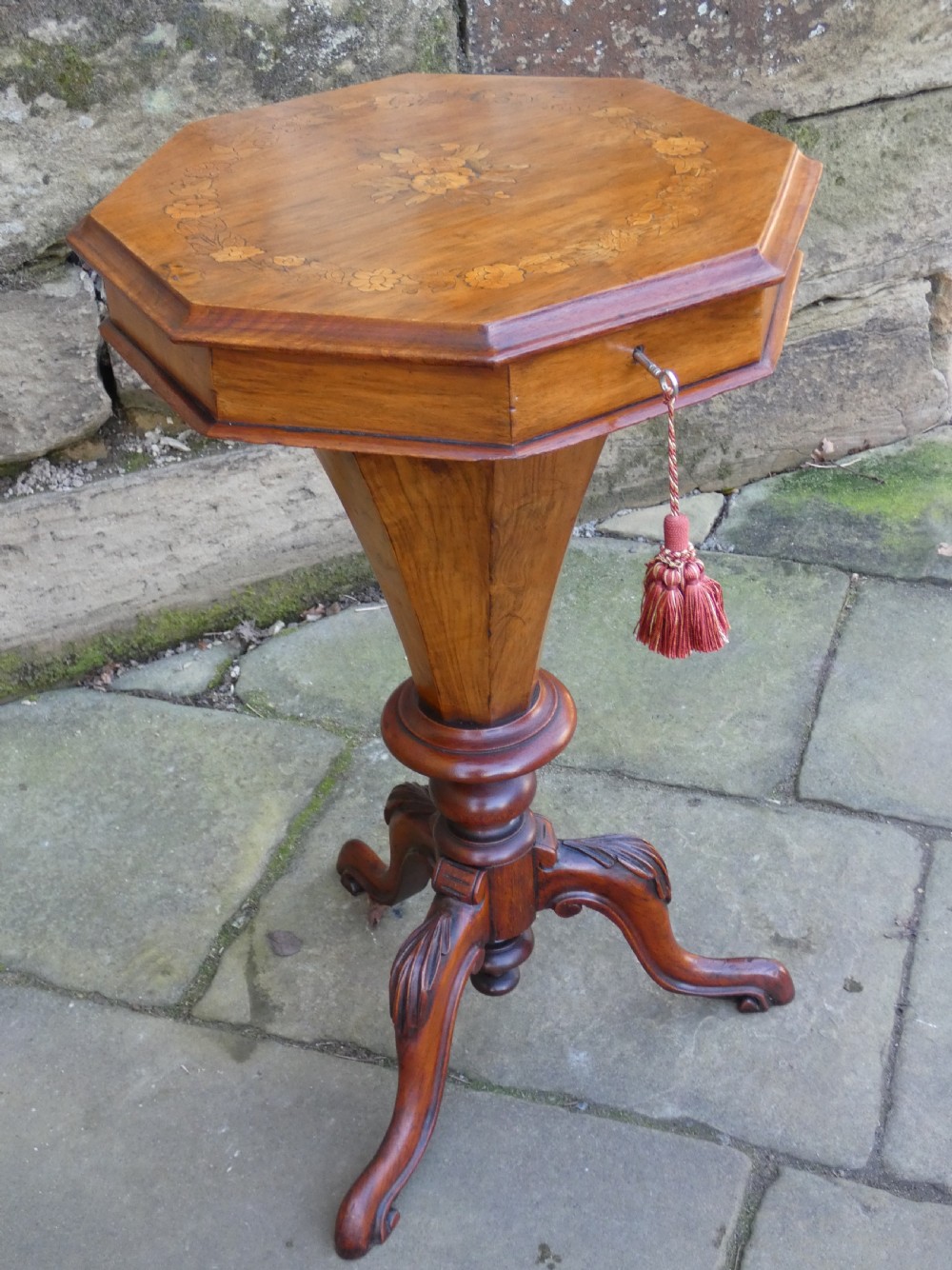 An octagonal Victorian rosewood sewing table featuring floral marquetry inlay on the top, a tapered trumpet base, and carved tripod feet.