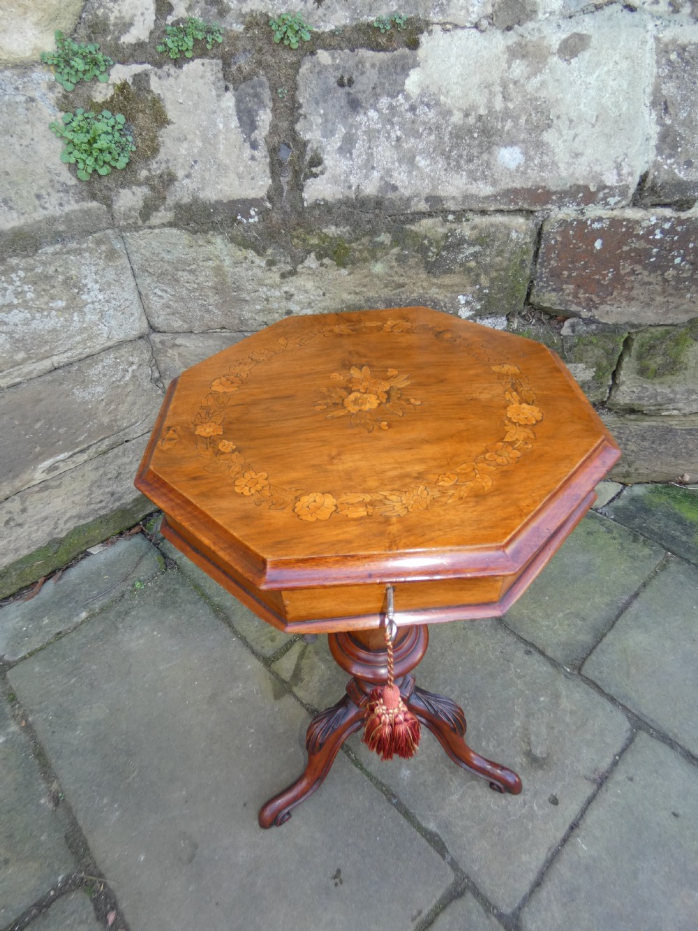 An octagonal Victorian rosewood sewing table featuring floral marquetry inlay on the top, a tapered trumpet base, and carved tripod feet. View II