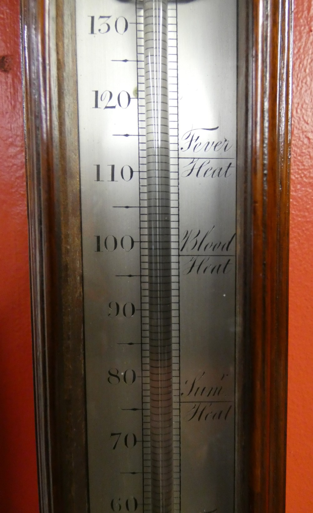 An antique Georgian mahogany stick barometer featuring a pediment with central finial, silvered register plate, integral mercury thermometer, and turned cistern cover. View VII
