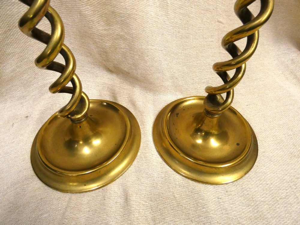 A pair of tall brass candlesticks featuring open barley twist stems and circular moulded bases. View II