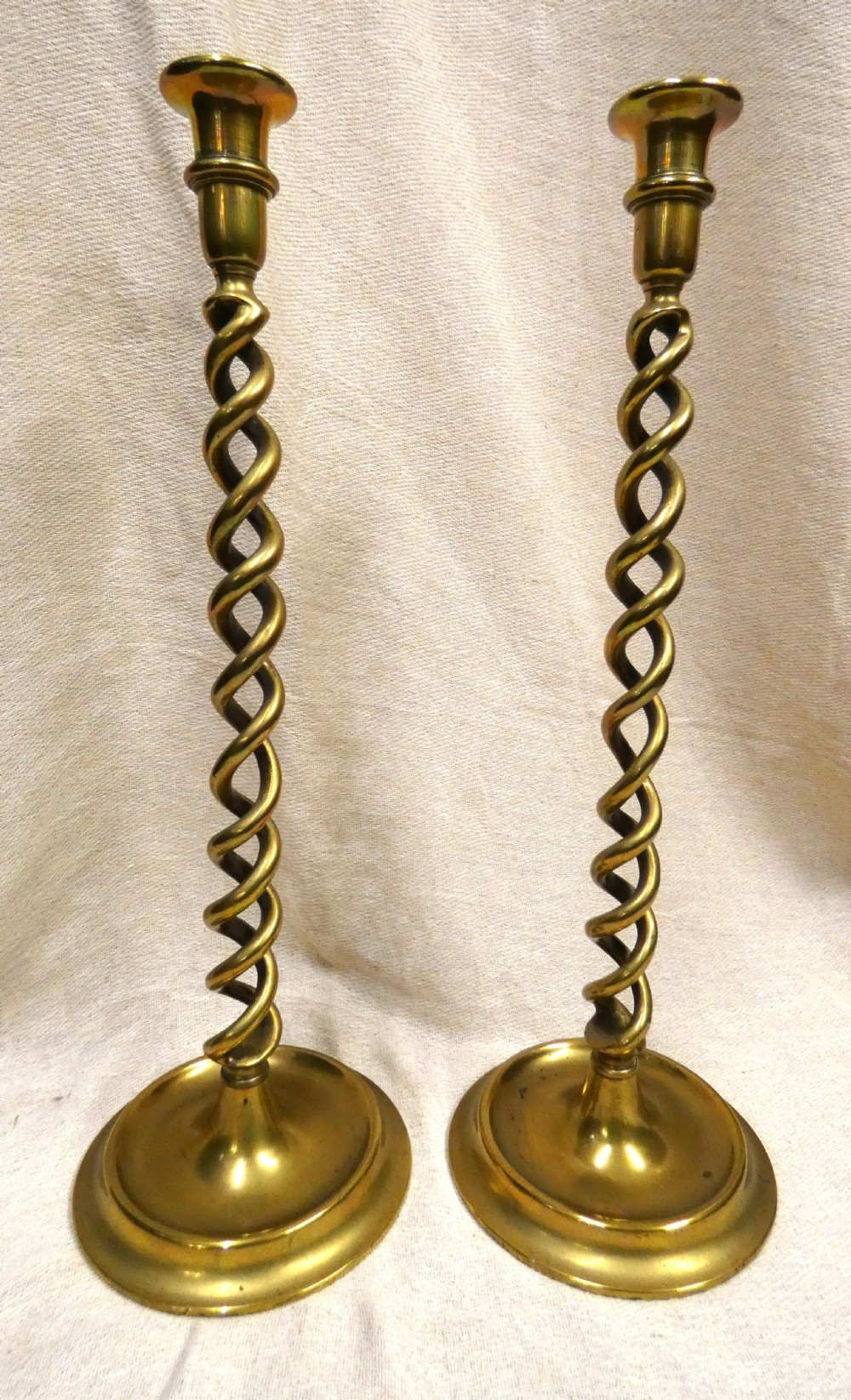 A pair of tall brass candlesticks featuring open barley twist stems and circular moulded bases. View VI