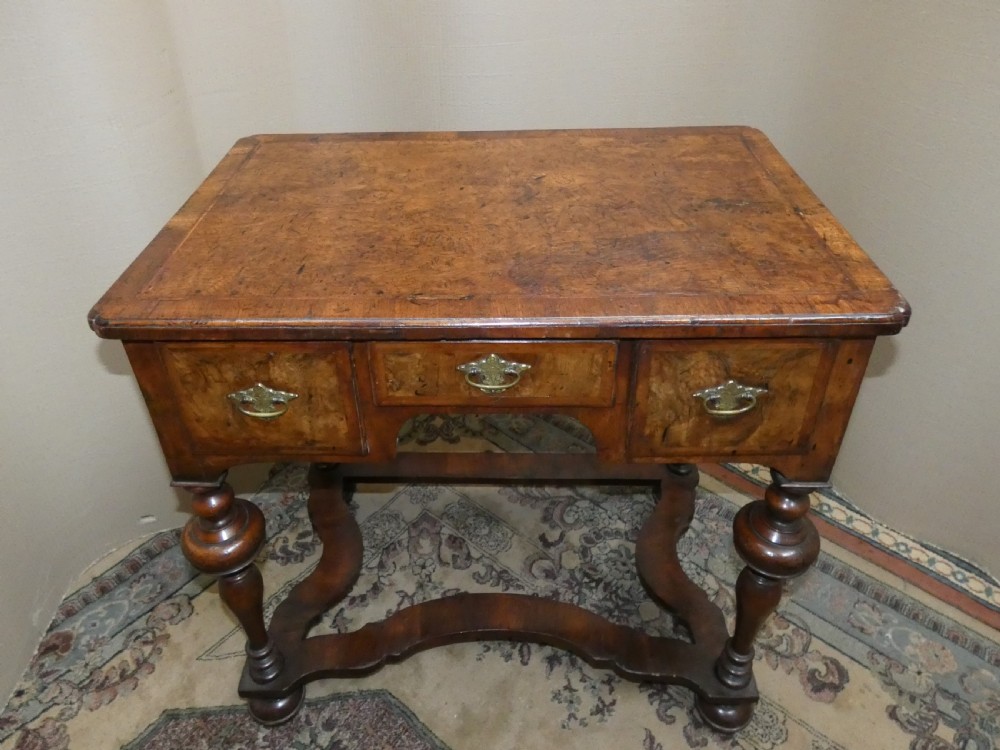 An 18th-century walnut lowboy table featuring three drawers with brass handles, turned legs, and a wavy shaped stretcher base. View II