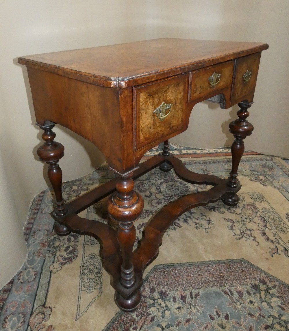 An 18th-century walnut lowboy table featuring three drawers with brass handles, turned legs, and a wavy shaped stretcher base. View VI