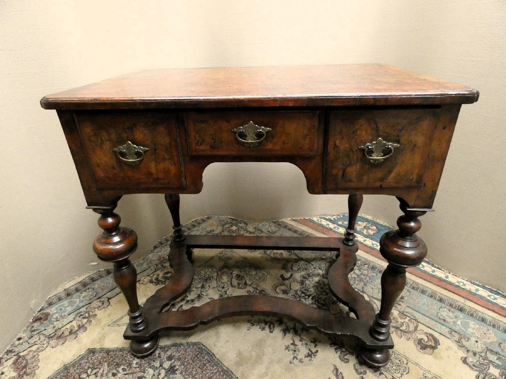 An 18th-century walnut lowboy table featuring three drawers with brass handles, turned legs, and a wavy shaped stretcher base. View VII