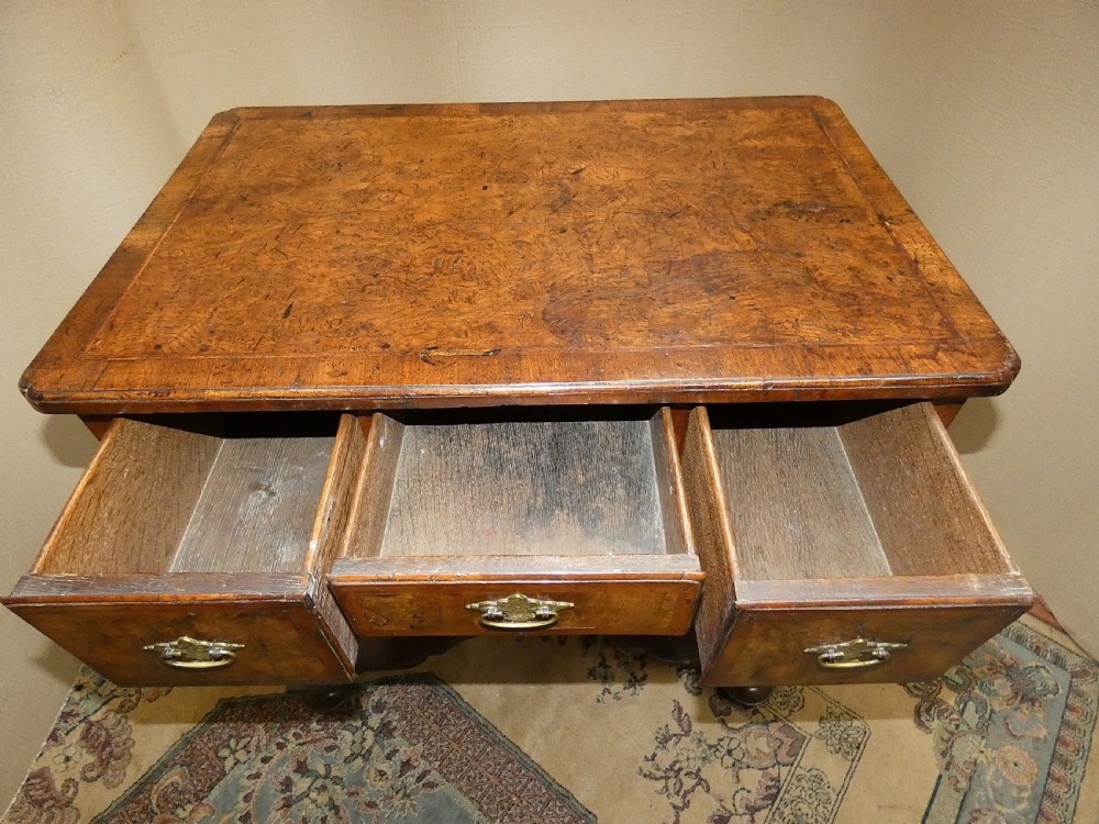 An 18th-century walnut lowboy table featuring three drawers with brass handles, turned legs, and a wavy shaped stretcher base. View VIII