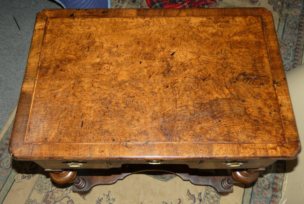 An 18th-century walnut lowboy table featuring three drawers with brass handles, turned legs, and a wavy shaped stretcher base. View IX