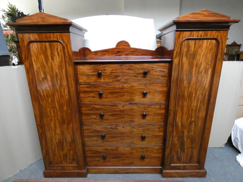 An antique Victorian mahogany combination wardrobe featuring a central stack of five drawers flanked by two tall flanking side cupboards with pediment tops. View II