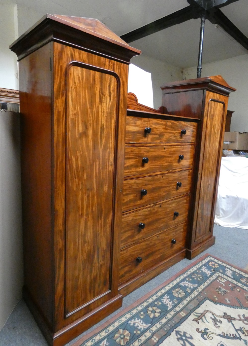 An antique Victorian mahogany combination wardrobe featuring a central stack of five drawers flanked by two tall flanking side cupboards with pediment tops. View III