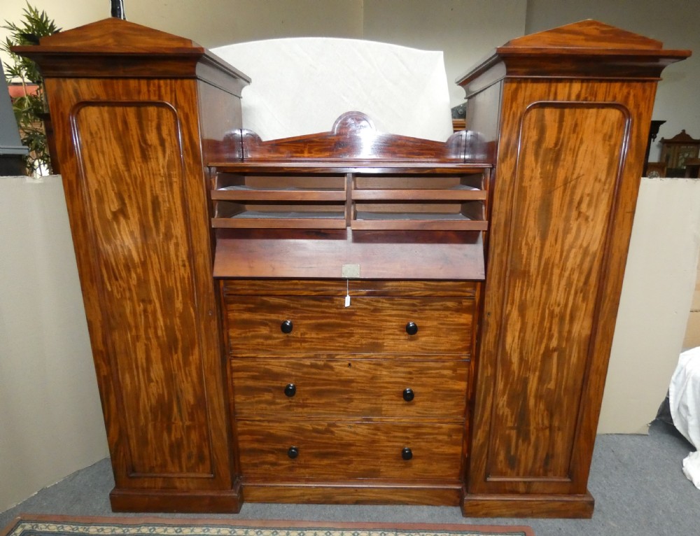An antique Victorian mahogany combination wardrobe featuring a central stack of five drawers flanked by two tall flanking side cupboards with pediment tops. View VI