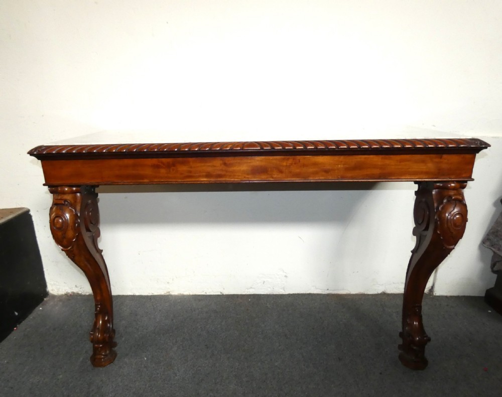 A William IV mahogany console table featuring a light marble top, gadrooned apron rim, and carved scroll front legs. View II