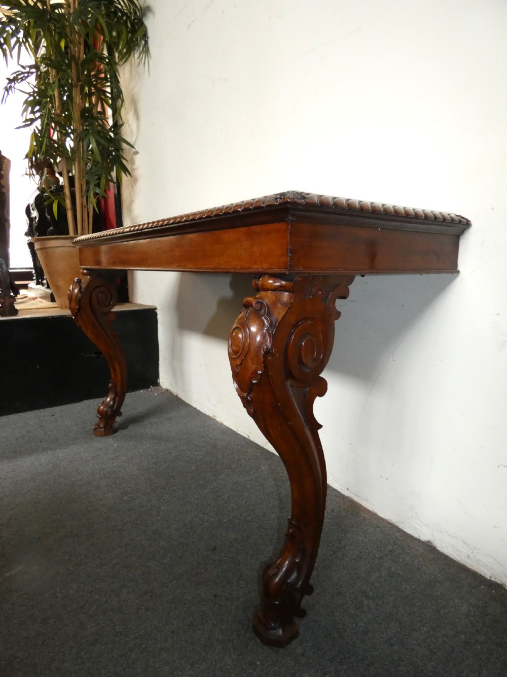 A William IV mahogany console table featuring a light marble top, gadrooned apron rim, and carved scroll front legs. View III