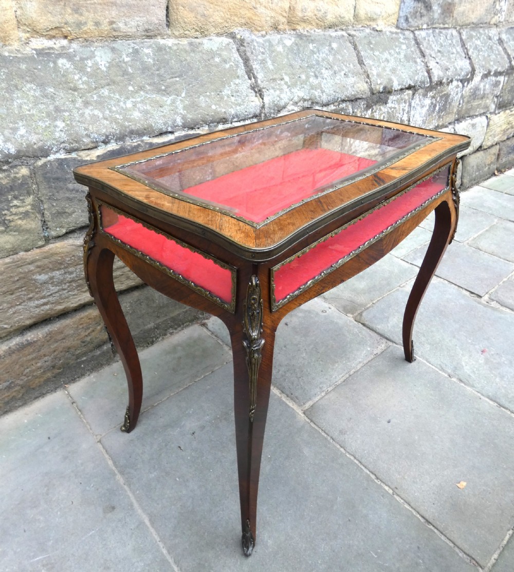 A French style rosewood bijouterie table featuring glass panels, red velvet interior lining, brass mounts, and cabriole legs. View II