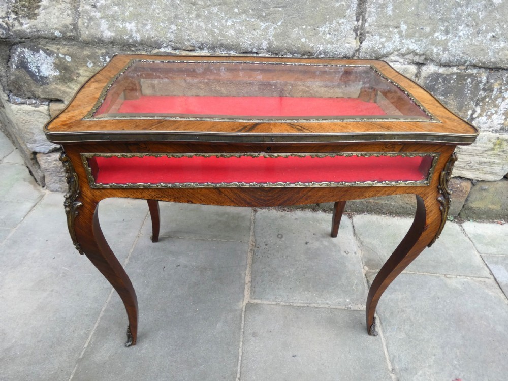 A French style rosewood bijouterie table featuring glass panels, red velvet interior lining, brass mounts, and cabriole legs. View III