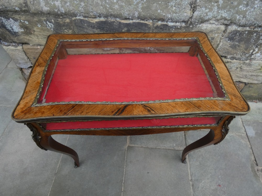 A French style rosewood bijouterie table featuring glass panels, red velvet interior lining, brass mounts, and cabriole legs. View V
