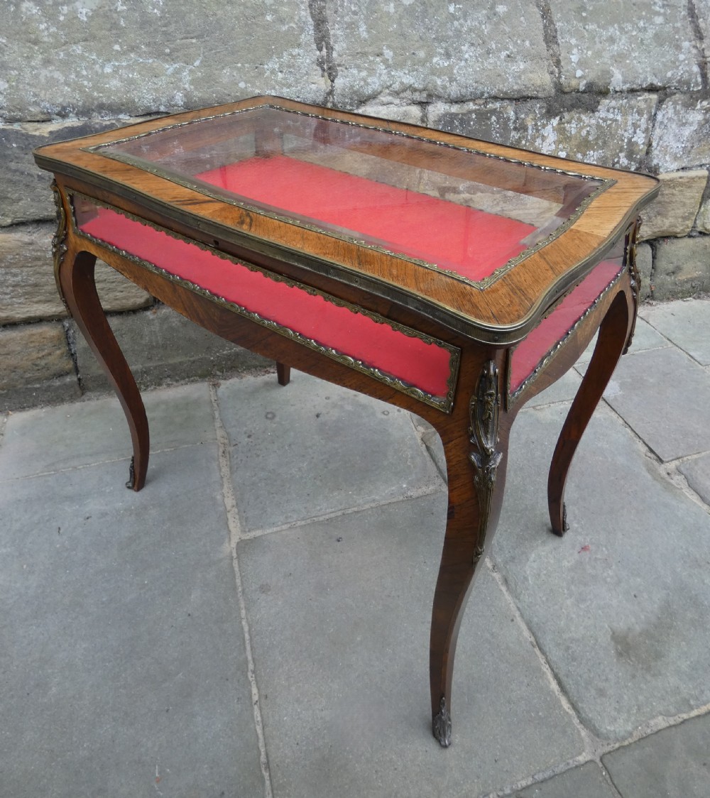 A French style rosewood bijouterie table featuring glass panels, red velvet interior lining, brass mounts, and cabriole legs. View VI