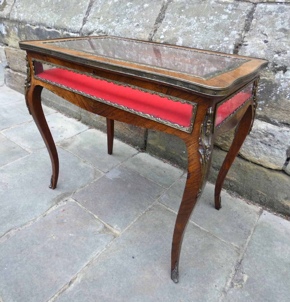 A French style rosewood bijouterie table featuring glass panels, red velvet interior lining, brass mounts, and cabriole legs. View VII