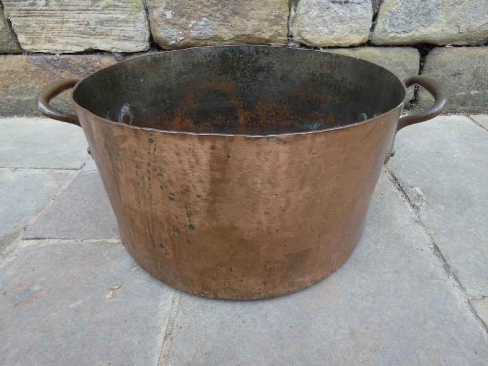 A large hand-hammered copper log bin featuring a wide cylindrical body, riveted side handles, and a natural aged patina with interior verdigris. View V