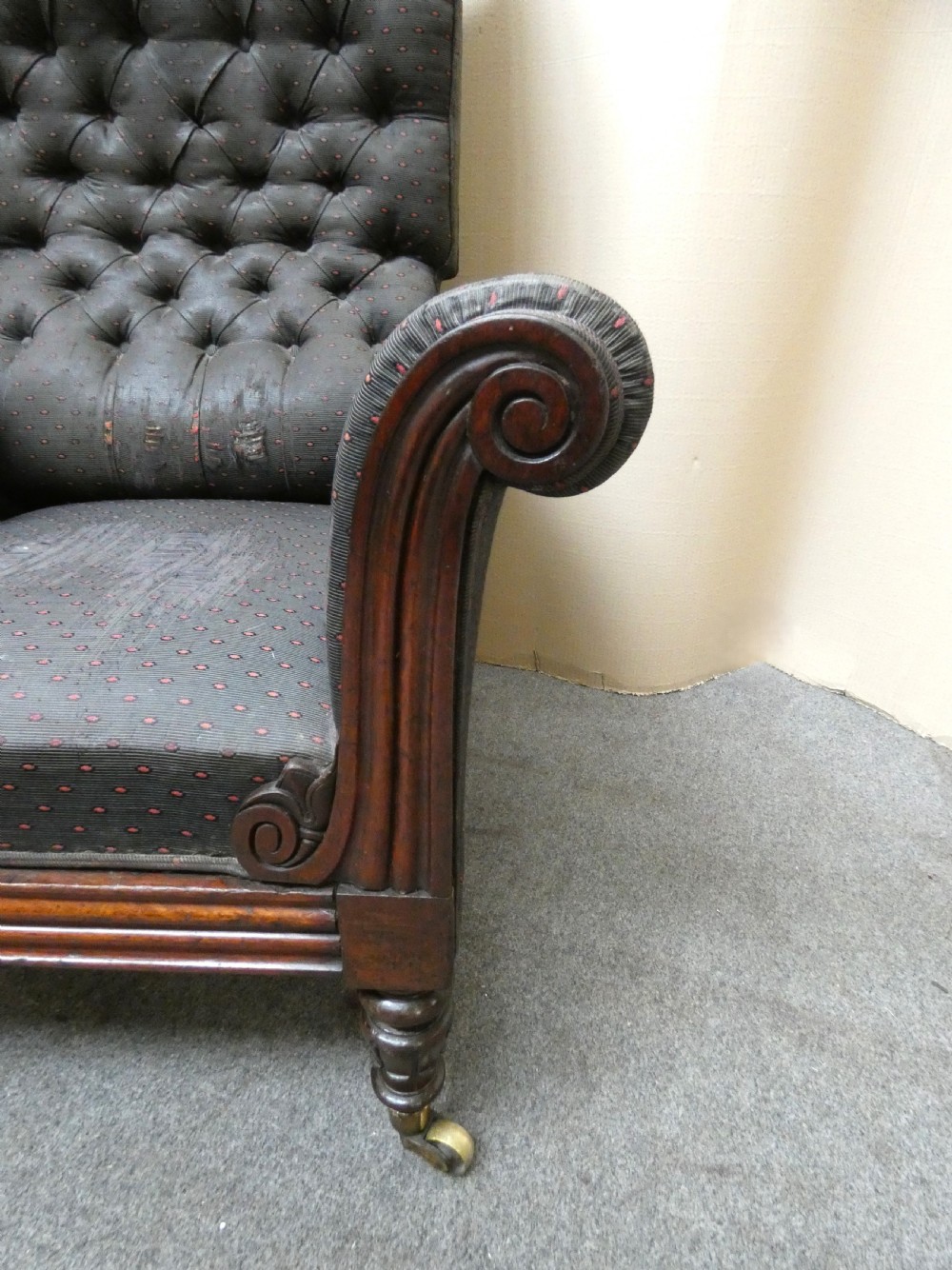A William IV reclining library armchair featuring dark button-backed upholstery, mahogany scroll-carved arms, and turned legs with brass castors. View III