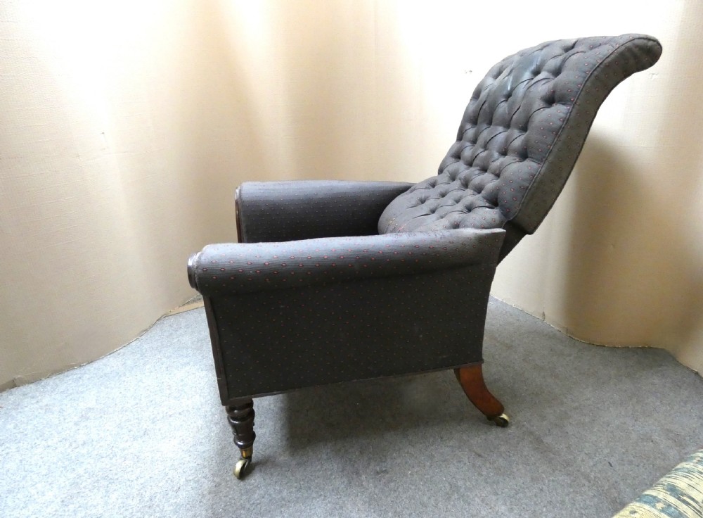 A William IV reclining library armchair featuring dark button-backed upholstery, mahogany scroll-carved arms, and turned legs with brass castors. View V