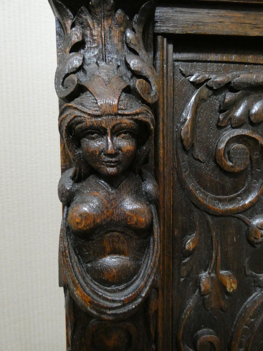 A dark carved oak high-back settle featuring three relief-carved back panels with portrait medallions, side caryatid figures, and a hinged storage seat above carved base panels. View VII