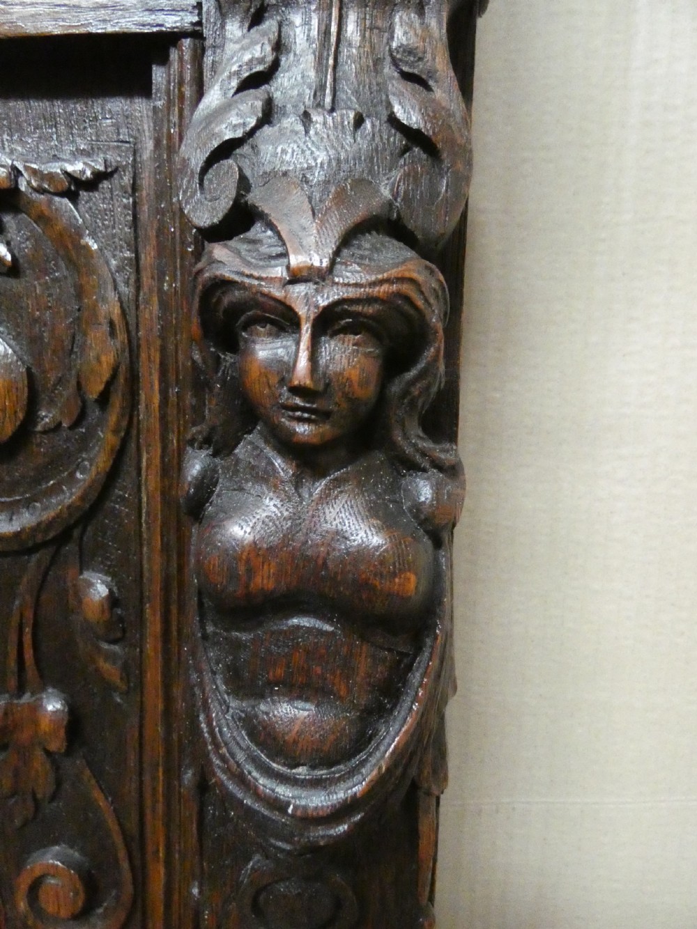 A dark carved oak high-back settle featuring three relief-carved back panels with portrait medallions, side caryatid figures, and a hinged storage seat above carved base panels. View VIII