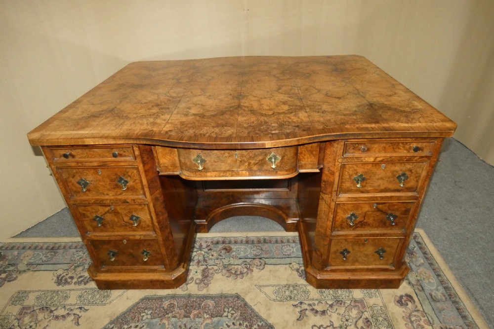 A large burr walnut partners desk featuring twin pedestals, multiple drawers with brass drop handles, and a crossbanded top surface. View II