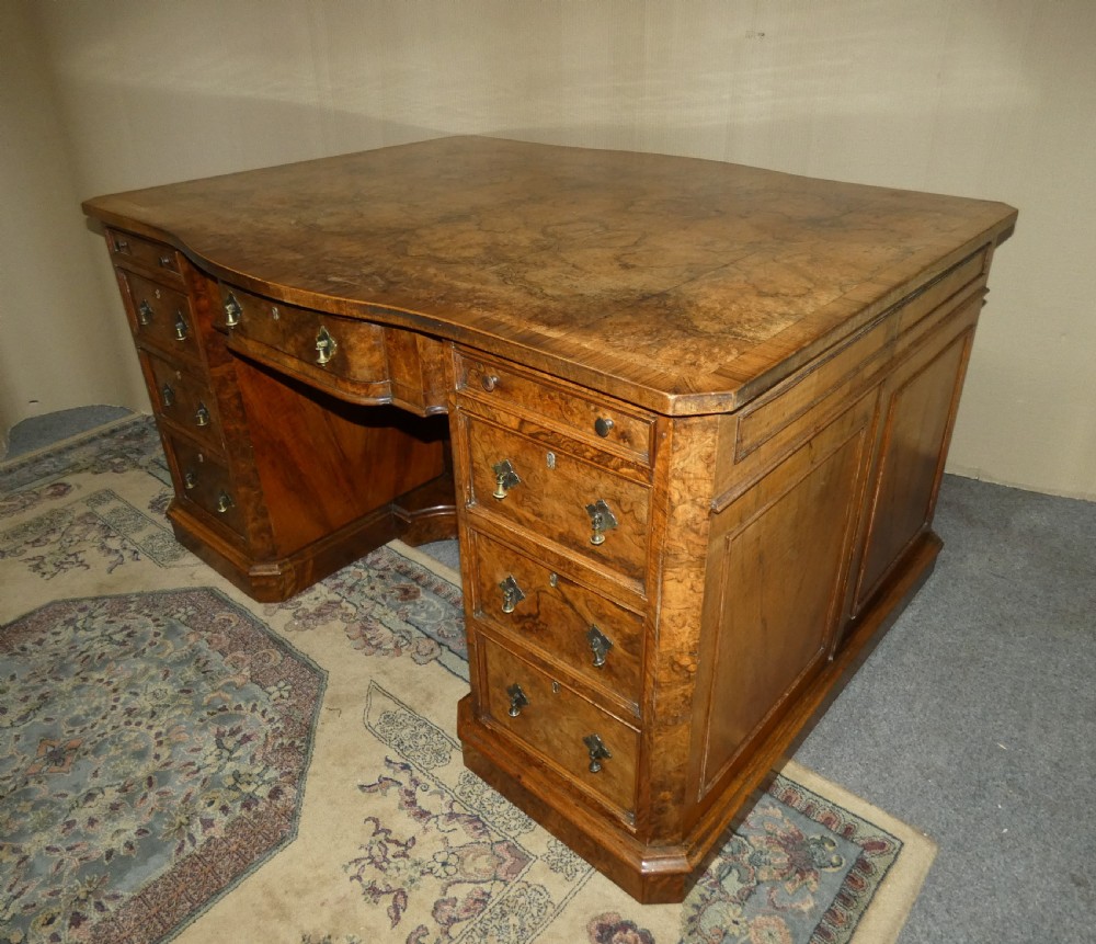 A large burr walnut partners desk featuring twin pedestals, multiple drawers with brass drop handles, and a crossbanded top surface. View III