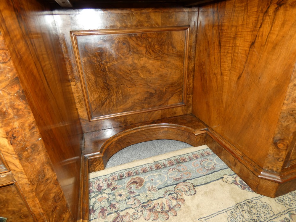 A large burr walnut partners desk featuring twin pedestals, multiple drawers with brass drop handles, and a crossbanded top surface. View V