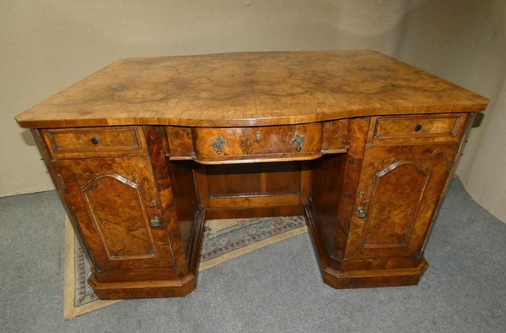 A large burr walnut partners desk featuring twin pedestals, multiple drawers with brass drop handles, and a crossbanded top surface. View VI