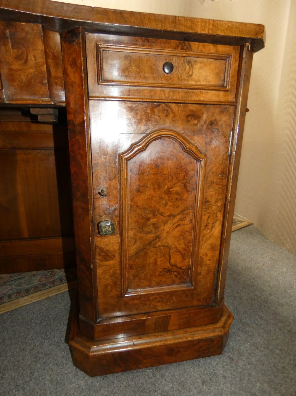 A large burr walnut partners desk featuring twin pedestals, multiple drawers with brass drop handles, and a crossbanded top surface. View VIII